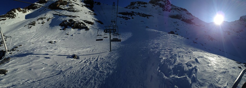 Early morning winter view from the Rosaël chairlift above Plan Bouchet in Orelle, capturing the first sunrise light and a clear blue sky before the ski slopes open.