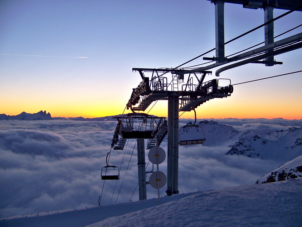 Sunset over a sea of clouds from Col Rosaël in Orelle, with glowing orange sky silhouetting the Aiguilles d'Arves and the top arrival station of the chairlift.