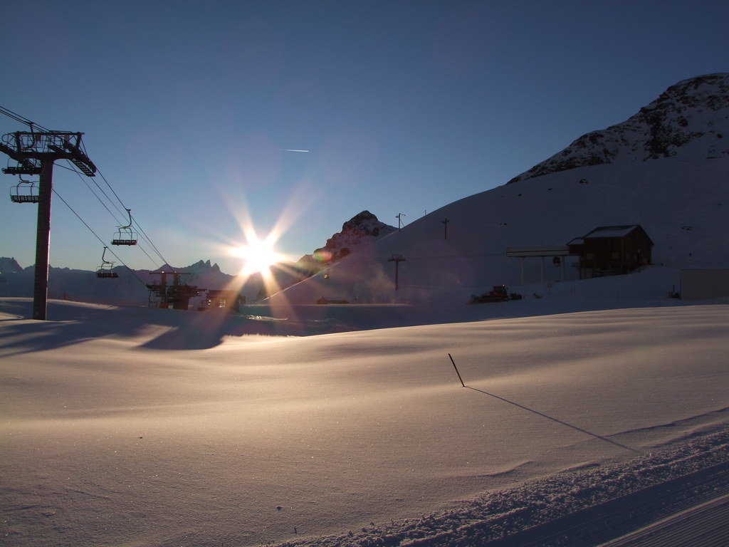 Vintage sunset view at Plan Bouchet in Orelle, showing the former Orelle cable car arrival station, Peyron chairlift departure, and Aiguilles d'Arves in the background.