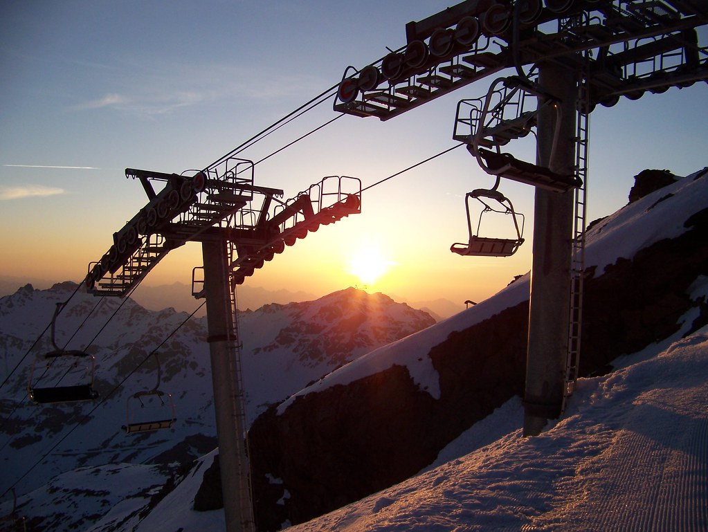 Sunset over Cime Caron cable car station in the distance, with the arrival of the Bouchet chairlift in Orelle in the foreground as shadows cover the vast ski area.