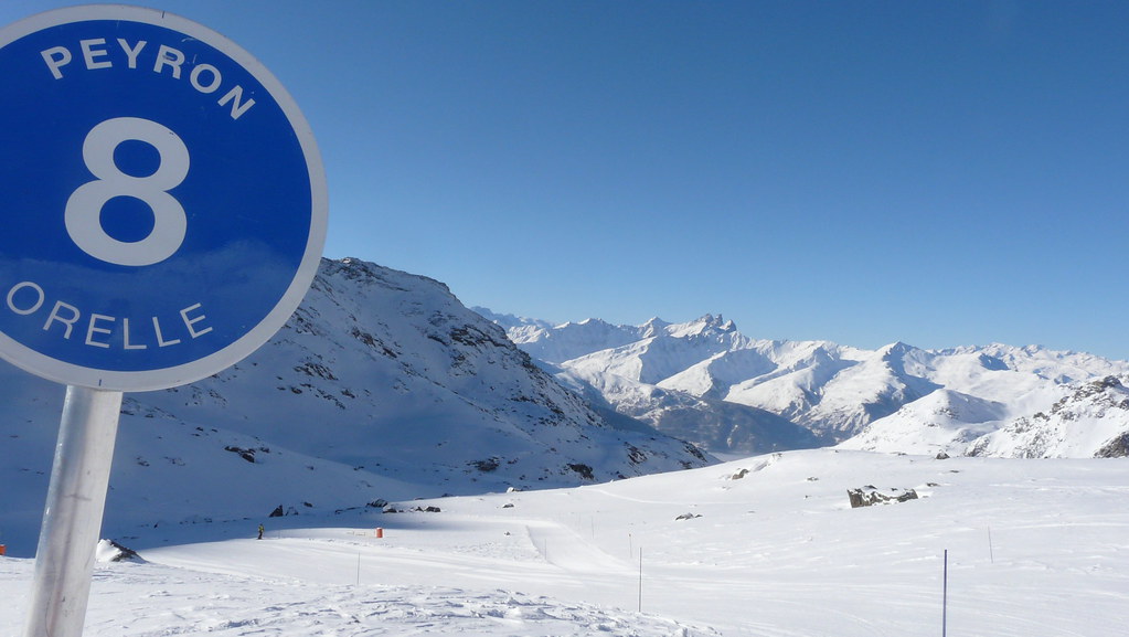 Blue sky panoramic view of the Peyron ski slope in Orelle with slope marker sign number 8 on the side under bright sunshine.