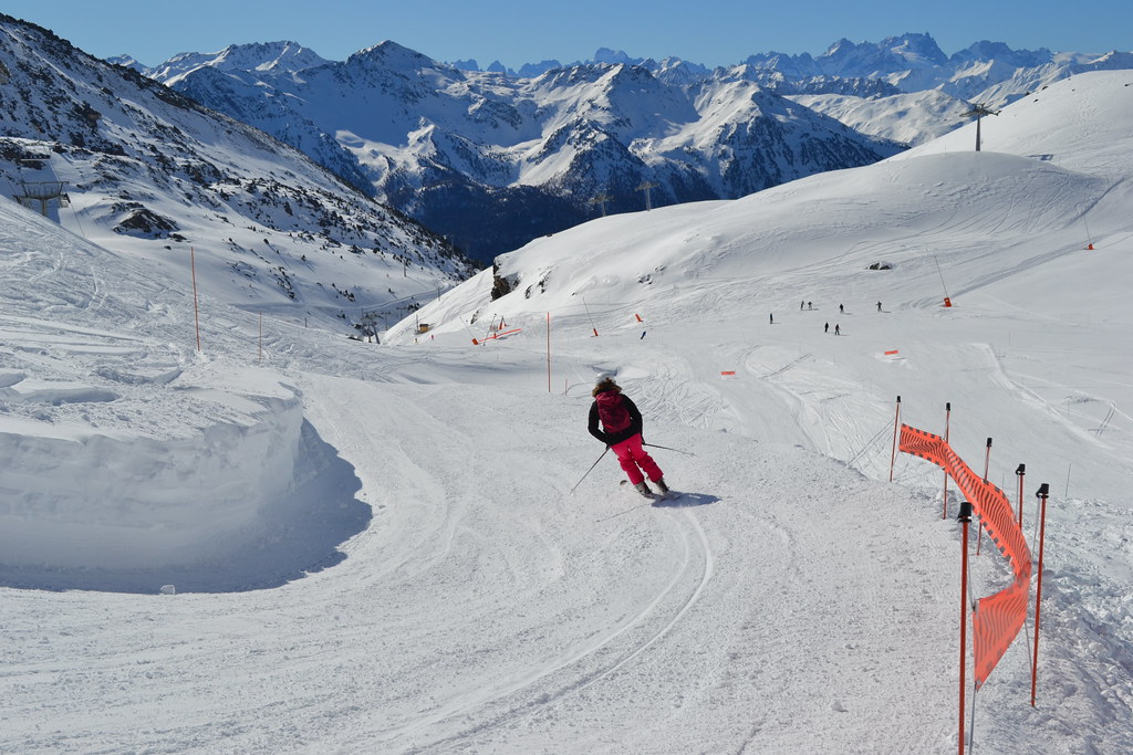 Female skier executing a turn on the Croix d'Antide slope near the intersection with Lory and Mauriennaise runs above Plan Bouchet station in Orelle.